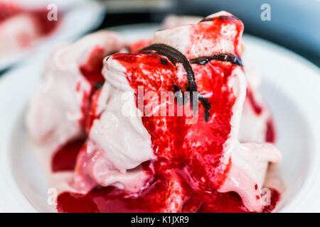Weiche Vanille Eis mit roten Erdbeer Sauce servieren und beträufelt Schokolade Sirup Nahaufnahme in der Schüssel Stockfoto