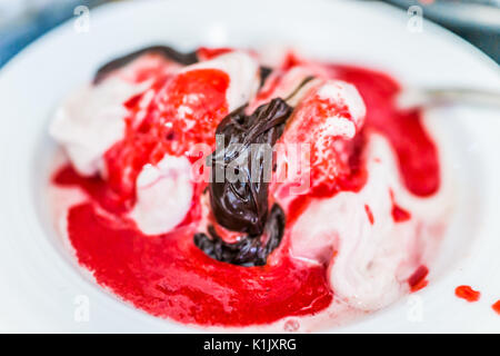 Weiche Vanille Eis mit roten Erdbeer Sauce servieren und beträufelt Schokolade Sirup Nahaufnahme in der Schüssel Stockfoto