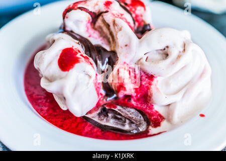 Weiche Vanille Eis mit roten Erdbeer Sauce servieren und beträufelt Schokolade Sirup Nahaufnahme in der Schüssel Stockfoto