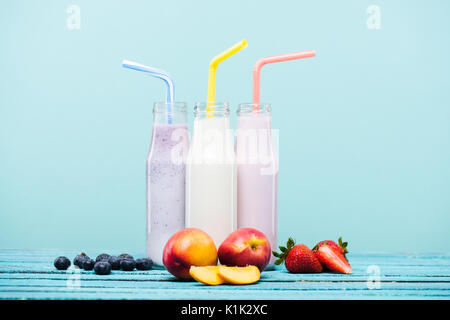 Nahaufnahme der verschiedenen Milchshakes in Glasflaschen und frische Früchte auf hölzernen Tisch Stockfoto