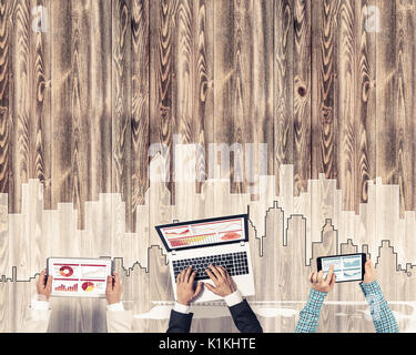 Gruppe von drei Personen mit Geräten in Händen arbeiten zusammen als Symbol der Vernetzung und Kommunikation Stockfoto