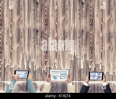 Gruppe von drei Personen mit Geräten in Händen arbeiten zusammen als Symbol der Vernetzung und Kommunikation Stockfoto