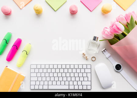 Blick von oben auf die Tastatur mit Maus, Blumenstrauß aus rosa Tulpen und Bürobedarf isoliert auf weißem Stockfoto