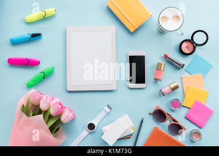 Flach mit Smartphone, Tablet, diverses Zubehör und Blumen auf blau isoliert Stockfoto