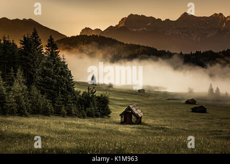 Kleine Hütte auf einer Wiese am Waldrand, Geroldsee im Hintergrund Karwendelgebirge bei Sonnenaufgang, Kaltenbrunn Stockfoto