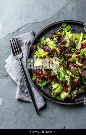 Blattsalat mit Granatapfel auf schwarze Platte, Schiefer-Hintergrund Stockfoto