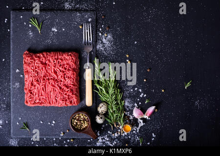 Rohe frische Lamm Fleisch und Fleischerzeugnisse Gabel auf dunklem Hintergrund, Burger patty Zutaten. Ansicht von oben. Freien Speicherplatz. Stockfoto