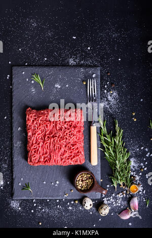 Raw marmoriertes Fleisch Steak mit Rosmarin, Salz und Pfeffer auf Stein Schiefer Hintergrund. Ansicht von oben, kopieren. Stockfoto