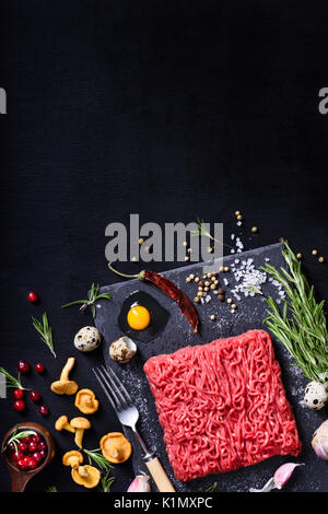 Rohes Fleisch. Rohes Rindfleisch Steak Hackfleisch auf einem Schneidebrett mit Rosmarin und Gewürzen. Über anzeigen, kopieren. Stockfoto