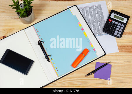Eingetopfte Kakteen Pflanze auf einem Buchhalter Schreibtisch aus Holz mit einem calculatorand ein smart phone auf einem Ordner öffnen Stockfoto