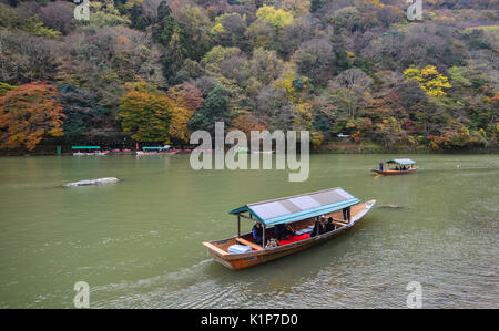 Kyoto, Japan - 28.November 2016. Boatman stochern das Boot für Touristen im Herbst Blick entlang der Ufer des Flusses Hozu in Arashiyama, Kyoto, Japan zu genießen. Stockfoto