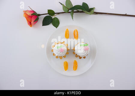 Kuchen Körbe mit Sahne und Orangenscheiben auf einer Platte am weißen Tisch und erhob sich. Ansicht von oben. Stockfoto