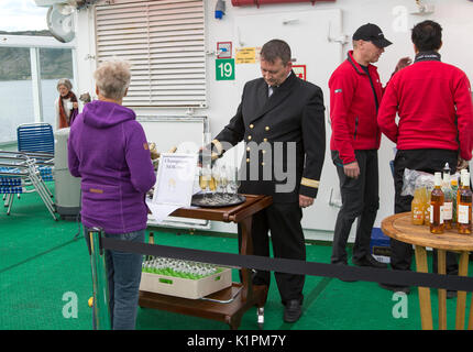 Champagner feier Überquerung des Polarkreises in Richtung Süden, Norwegen Hurtigruten Fähre Schiff, Offizier in Gläser gießen von der Flasche Stockfoto