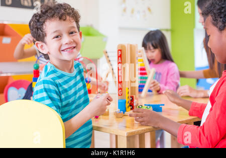 Kindergarten Studenten lächeln, wenn Spielzeug spielen im Spielzimmer an der Vorschule international, Bildung Konzept. Stockfoto