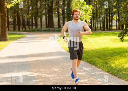 Runner im Park. Jungen athletischen Mann Joggen am Morgen. Fitness Modell in crossfit Übung im Freien. Gesunder Lebensstil Konzept. Stockfoto