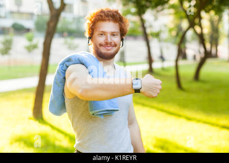 Junge erwachsene Mann zeigt Smart watch oder Fitness Tracker, lächelnd und mit Blick auf die Kamera. Stockfoto