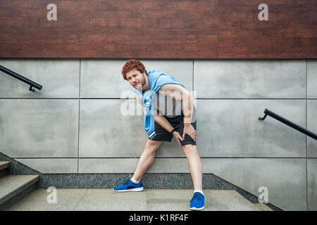 Sport Verletzung. Verletzte Runner, bärtigen Mann mit Sommersprossen athletischen Körper auf der Laufstrecke Schmerzen im Kniegelenk. Outdoor Sommer Aktivität, Sport. Gesund l Stockfoto