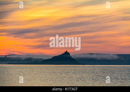 Penzance und Marazion, Cornwall, UK. 28. August 2017. UK Wetter. Am frühen Morgen Nebel begann bei Sonnenaufgang über St. Michaels Mount, wo der rote Fluss, der ins Meer läuft mit Marazion zu heben. Wie von Penzance gesehen, dann der Strand von Marazion kurz nach Sonnenaufgang. Foto: Simon Maycock/Alamy leben Nachrichten Stockfoto