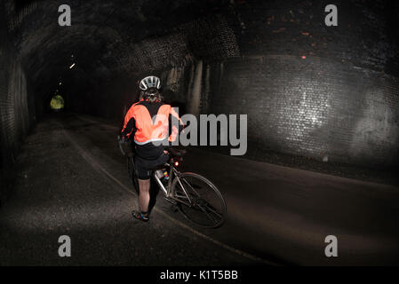 Weibliche Radfahrer in einem Tunnel auf der Monsal Trail, Bakewell, Derbyshire, UK. Stockfoto