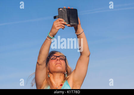 Eine junge Frau nimmt Fotos Videos mit dem Handy am Strand. Stockfoto