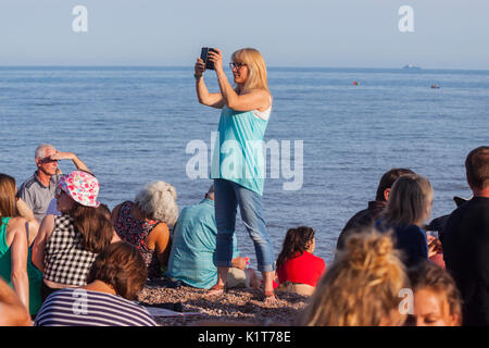 Eine junge Frau nimmt Fotos Videos mit dem Handy am Strand. Stockfoto