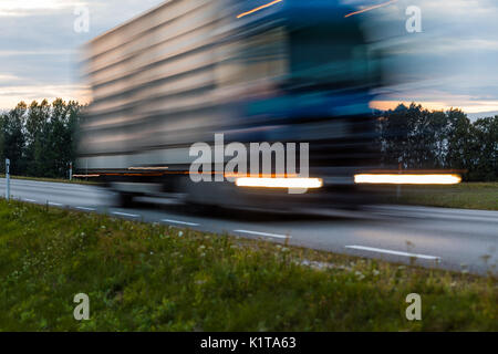 Beschleunigung Bewegungsunschärfe entgegenkommenden Lkw mit glühenden Lichter auf der Autobahn nach Sonnenuntergang. abstract blur Bild Hintergrund mit kopieren. Stockfoto