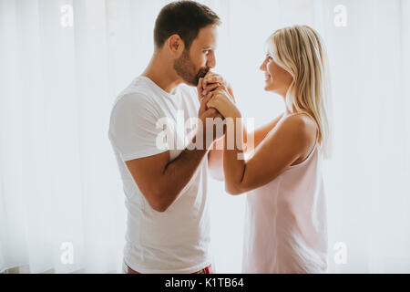 Junger Mann küsst jungen womans Hand im Zimmer neben dem Fenster Stockfoto