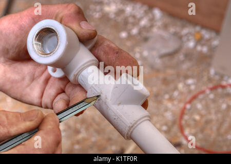 Der Klempner macht Markierungen auf Kunststoff Armaturen mit Bleistift, Nahaufnahme der Hand. Stockfoto