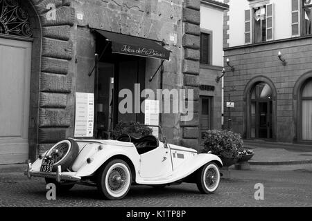 Vintage White Auto vor einem Geschäft geparkt, auf einem öffentlichen Platz in Orvieto, gedreht in Schwarz und Weiß. Spiegelt den alten Charakter von Orvieto. Stockfoto