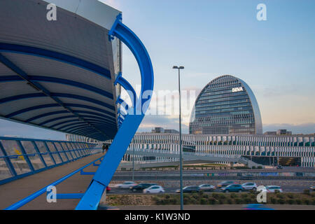 La Vela Gebäude- und Fußgängerbrücke über die Autobahn A1 bei Einbruch der Dunkelheit. Sanchinarro, Madrid, Spanien. Stockfoto