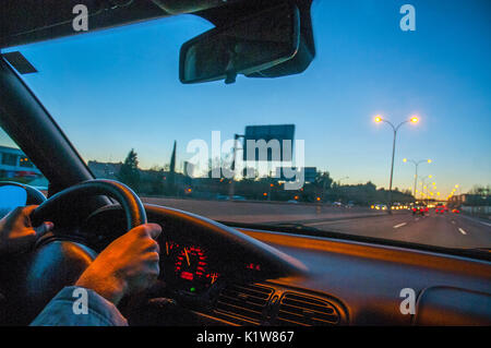 Die Hände des Menschen ein Auto fahren bei Einbruch der Dunkelheit. Stockfoto