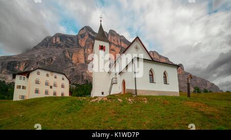 Die Kirche und das Hospiz von Santa Croce in Alta Badia am Fuße des riesigen Westwand des Sasso della Croce, Dolomiten, Südtirol Stockfoto