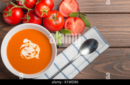 Tomatensuppe mit frischen Tomaten und Sahne auf einen hölzernen Tisch serviert Stockfoto