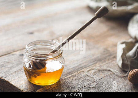 Krug Honig und Honig Pendelarm auf hölzernen Tisch Stockfoto