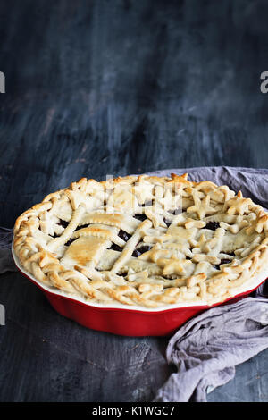 Sweet Blueberry Pie mit Gitter und Sterne Kruste in einem roten Kreis Platte gegen einen rustikalen Holzmöbeln Hintergrund. Stockfoto