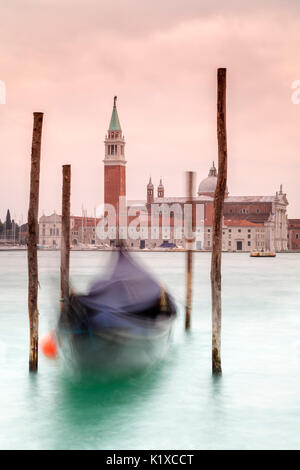 Europa, Italien, Veneto, Venedig. Gondeln an Holzstangen am Canal Grande, im Hintergrund das Kloster von San Giorgio Maggiore gefesselt Stockfoto