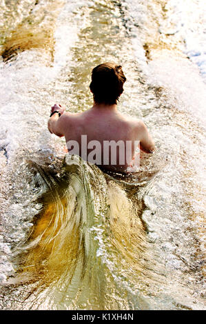 Junger Mann gleiten auf einem Damm überlauf Wasser schieben. Stockfoto