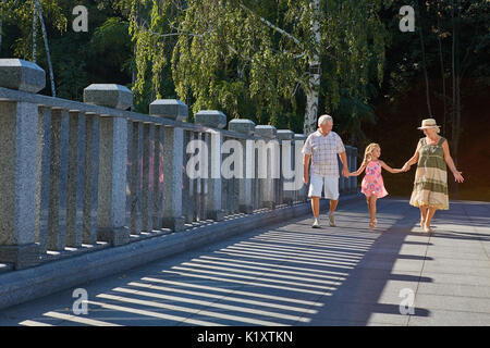 Mädchen mit Großvater und Großmutter. Familie wandern, Sommertag. Bei einem Spaziergang durch den Park. Stockfoto