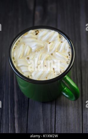 Heißes Getränk mit weißen Marshmallows in einem grünen Emaille Tasse auf einem schwarzen Holztisch Ansicht von oben. Dunklen Hintergrund. Platz für Text. Stockfoto