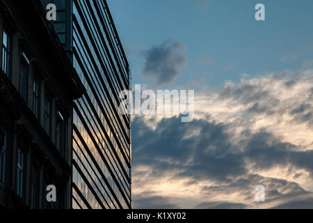 Moderne Gebäude aus Glas verwendet, als Büro Platz in den Sonnenuntergang mit einem älteren Gebäude gleich neben ihm. Bild von einem modernen Bürogebäude Stockfoto