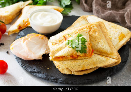Gedrückt und gerösteten double Sandwich mit Huhn, Koreanisch Karotten, Käse und Tomaten auf grauem Stein oder Schiefer. Stockfoto