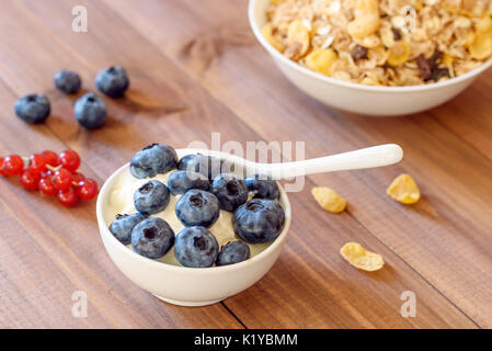 Schale Frühstück gesundes Müsli mit Blaubeeren, rote Johannisbeeren und Joghurt. Stockfoto