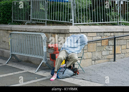 Ein unbekannter Mann, vermutlich obdachlos, schlafen während der späten Morgen im Union Square Park in Manhattan, New York City Stockfoto