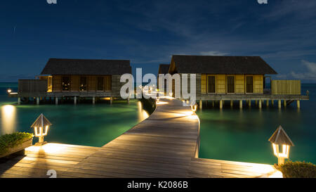 Holzhütten auf Stelzen in der Lagune bei Nacht, Gangehi Island, Ari Atoll, Malediven, Indischer Ozean Stockfoto