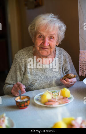 Ältere Frau Essen am Tisch zu Hause. Stockfoto