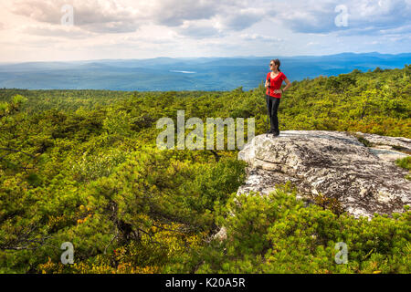 Frauen steht am Rand einer Klippe und genießt die Natur am höchsten Punkt, oben auf Shawangunk Ridge, in Upstate New York. Stockfoto