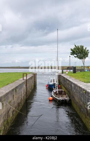 Galway, Irland - August 3, 2017: Auf der Suche nach zwei kleine Boote im Claddagh Dock, Teil des alten Hafens. Nimmo's Pier am Horizont bilden eine T-Symbol. Uhr Stockfoto