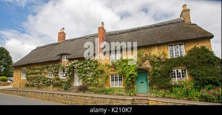 Panoramablick auf das malerische Reetdachhäuser mit bunten Garten in der Nähe von Dorf Hilcote, England Stockfoto
