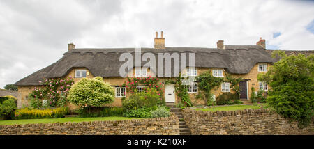 Panoramablick auf das malerische Reetdachhäuser mit bunten Garten in der Nähe von Dorf Hilcote, England Stockfoto