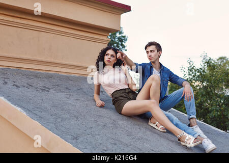 Die Teenager kletterten auf das Dach. Er verweist auf die Entfernung mit seinem Finger. Romantisches date. Stockfoto